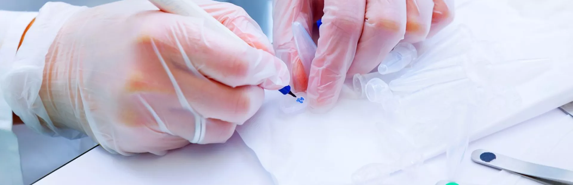 Scientist with gloves writing a number on a test tube