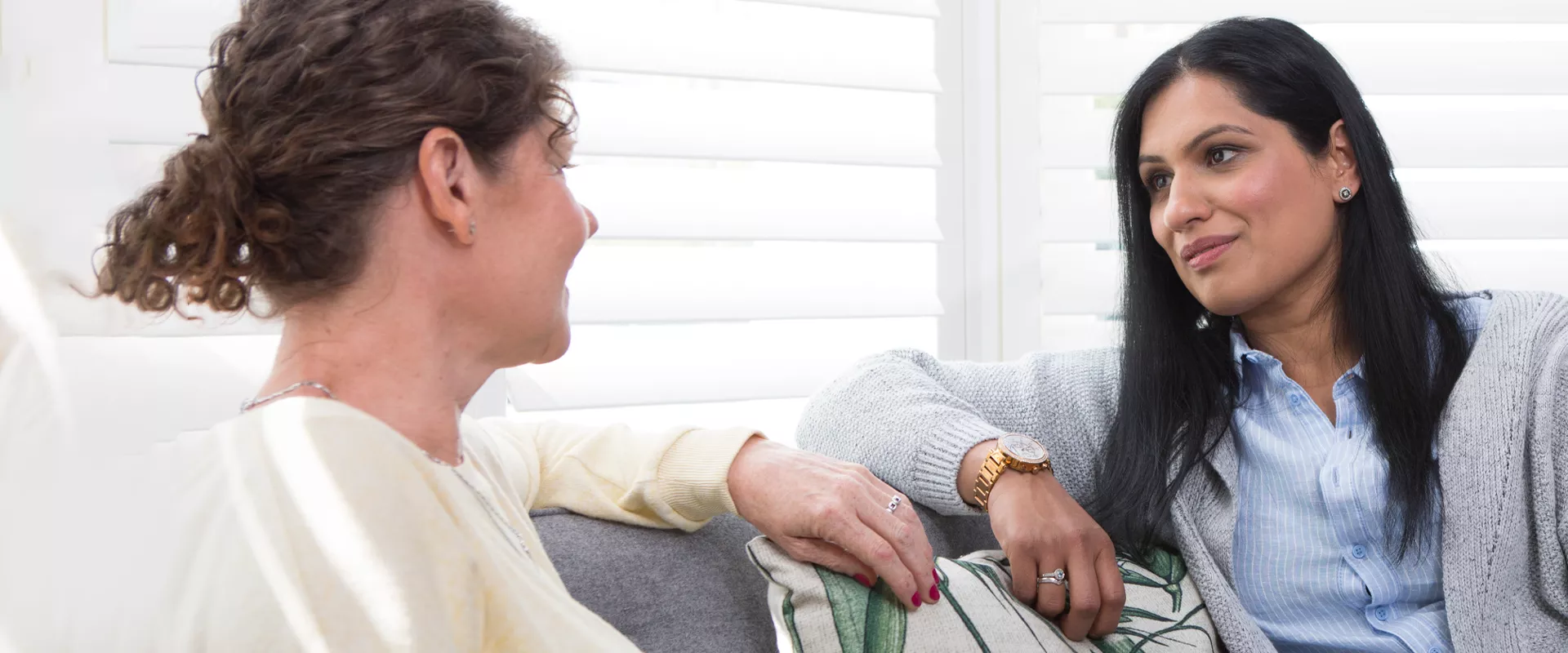 Two women, seated on a sofa, engaged in a conversation