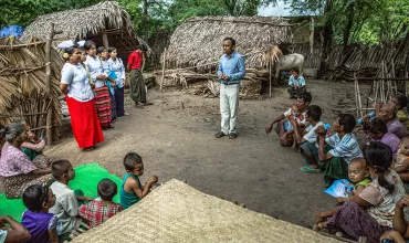 A man teaches a community in Myanmar about leprosy awareness and prevention 