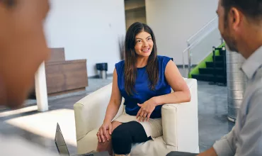 Three business people discussing sitting in armchair