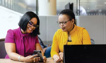 Two women in a conversation, looking at a phone