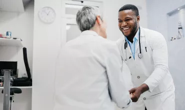 Medical professional and patient smiling and holding hands Medical professional and patient smiling and holding hands