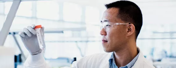 A Novartis scientist holding a test-tube in a lab