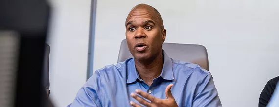 A black Novartis associate leading a meeting in a board room