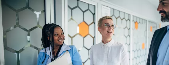 Three business people laughing in corridor