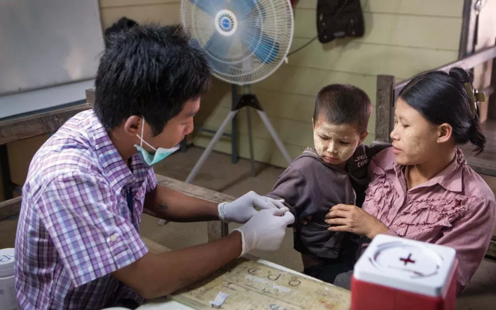 A healthcare worker drawing blood to verify if child’s symptoms are due to malaria.