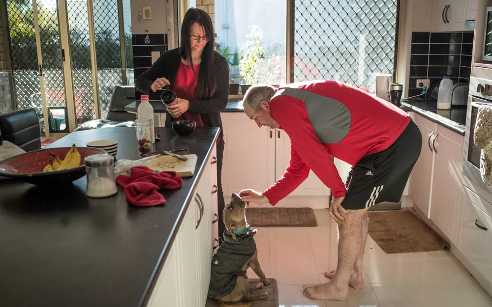 A man and a woman prepare food in their kitchen Mr. Caddies and his wife prepare food and feed their dog in their kitchen