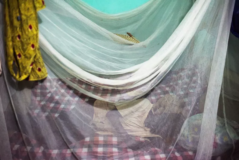 A person sleeps under a mosquito net in Bougoula. A person sleeps under a mosquito net in Bougoula.