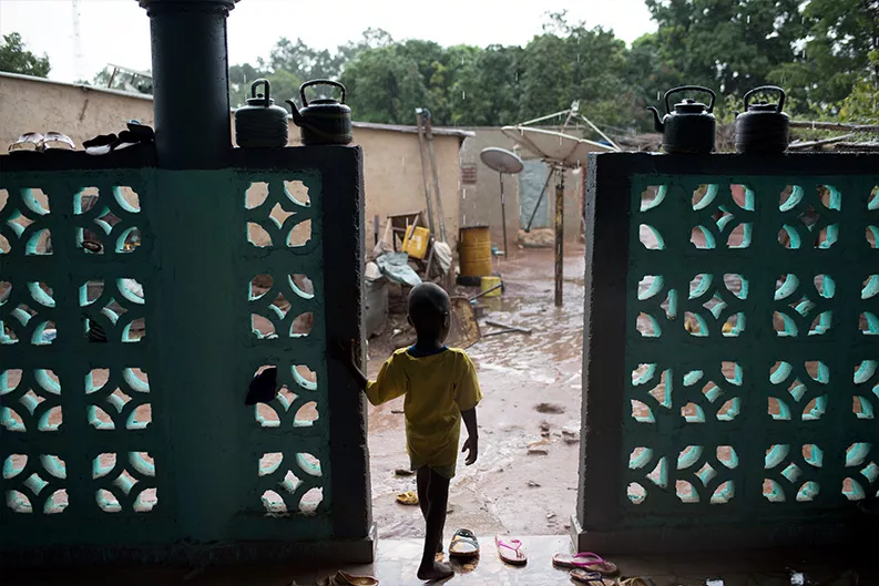 A young child watches the rain in the village of Bougoula. A young child watches the rain in the village of Bougoula.