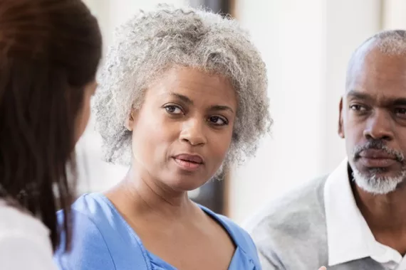 A woman, accompanied by her caregiver, shares her experiences with a doctor. A woman, accompanied by her caregiver, shares her experiences with a doctor.