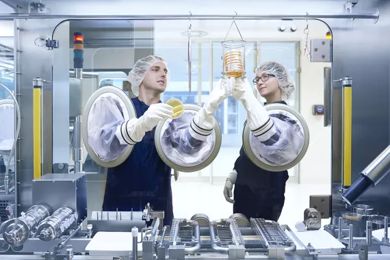 Two production specialists working with a complex manufacturing machine 