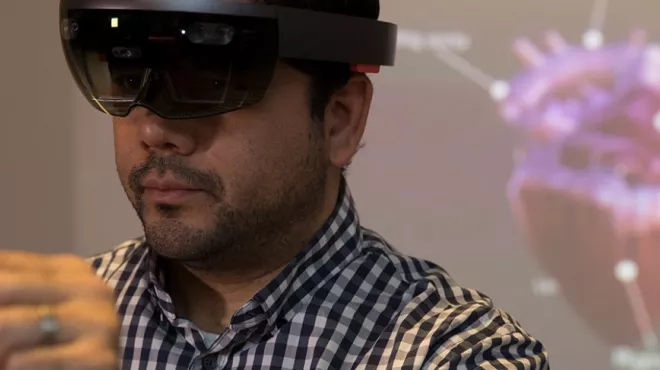 Man wearing AR glasses to manipulate a hologram of a heart