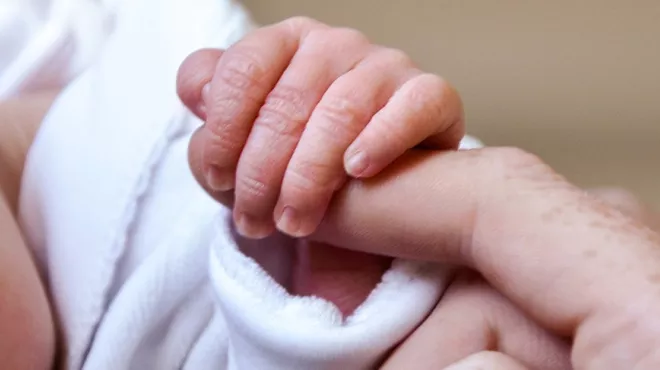 Baby's hand holding parent's finger