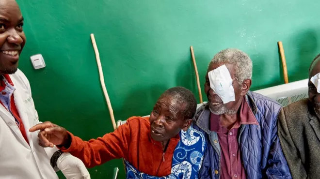 Dr. Theophile Tuyisabe standing next to his patients smiling at him