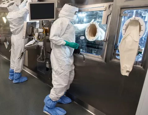 Two associates in full personal protective equipment stand at the production line