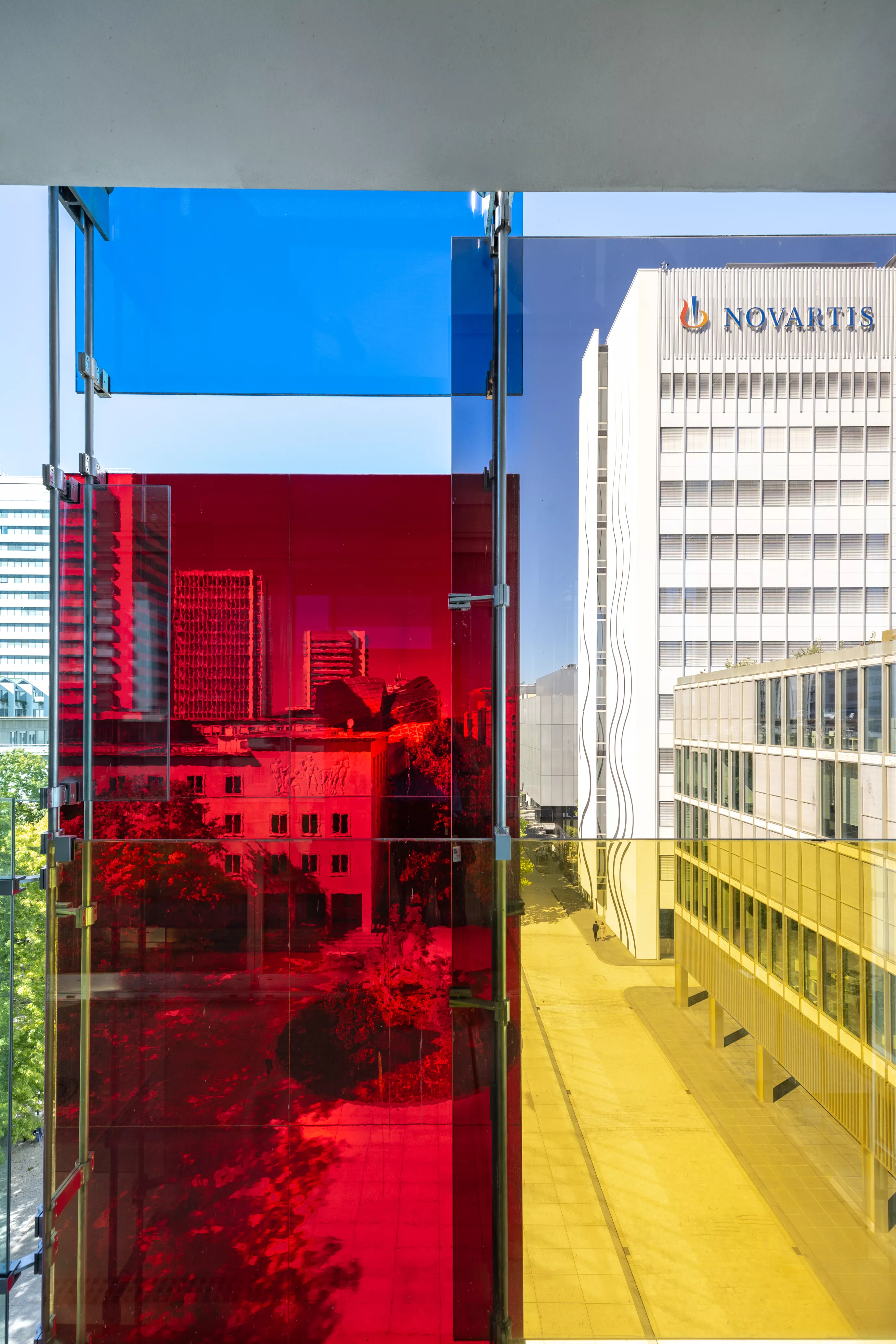 View of the Novartis logo through the colorful façade of Forum 3, Novartis Campus Basel (vertical) View of the Novartis logo through the colorful façade of Forum 3, Novartis Campus Basel (vertical)