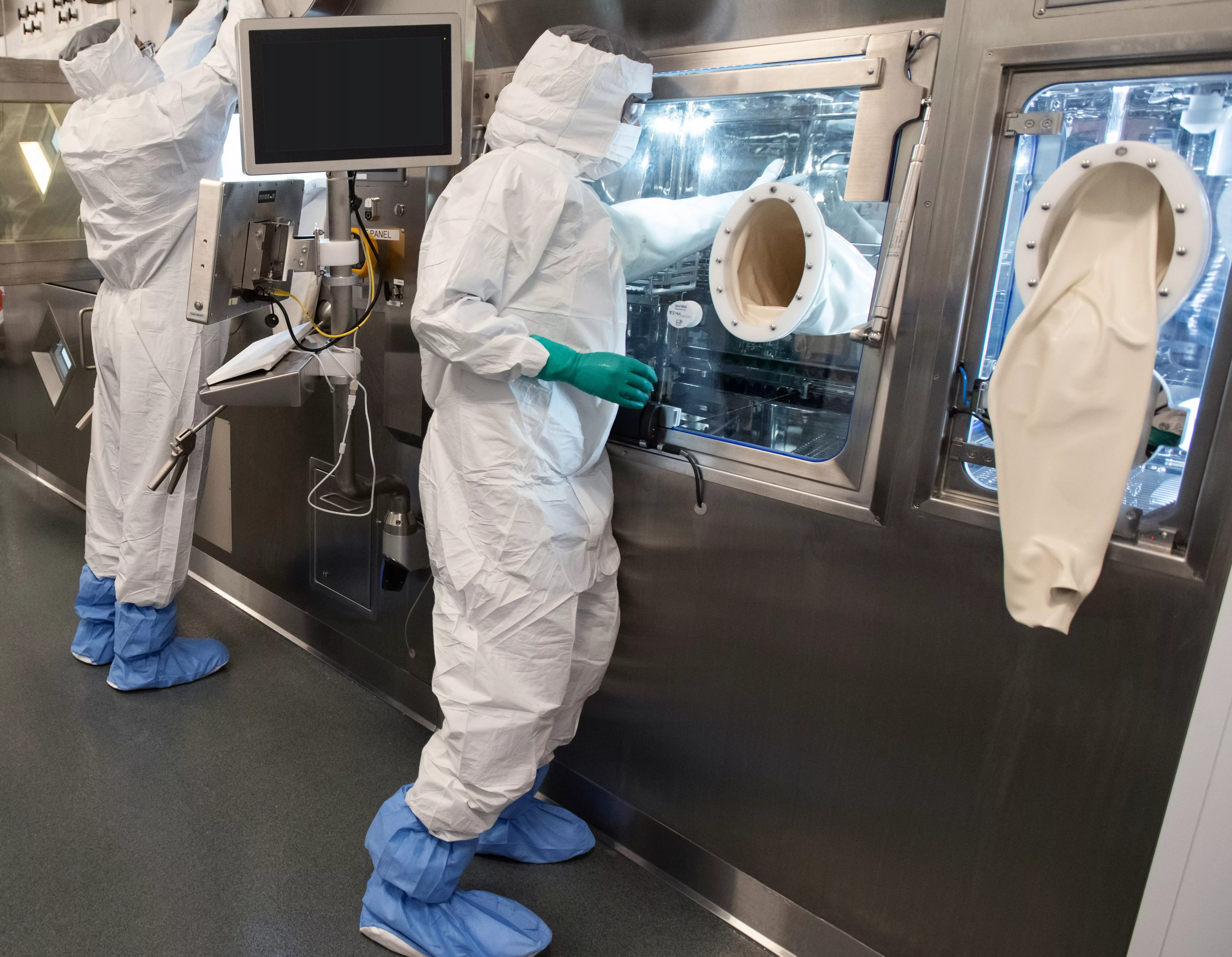 Two associates in full personal protective equipment stand at the production line